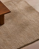 A wool rug with a thick, plush cut pile - the Valencia Dune by Weave Home, seen under the leg of a coffee table.