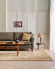 A stylish living room with a soft beige floor rug in sandy warm bamboo silk fibres and natural brown jute, handmade by Baya .