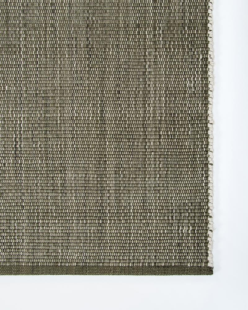 The Lonsdale outdoor rug by Baya, seen from above close enough to show the cream and olive green weave