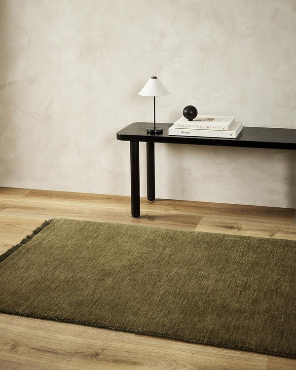 The olive green 'Moss' Sandringham wool runner rug by Baya, seen in a modern home with wooden floorboards.