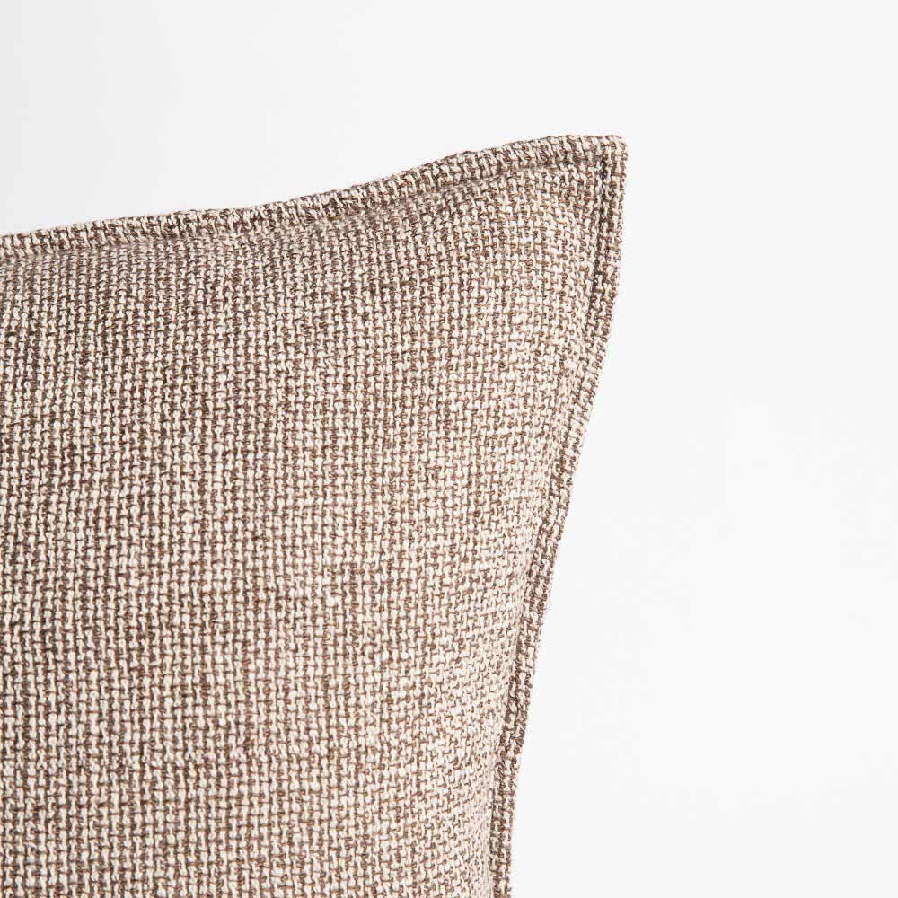A corner view of the Kenji cushion, showing the interwoven taupe and off-white threads, as well as the tapered hemline 