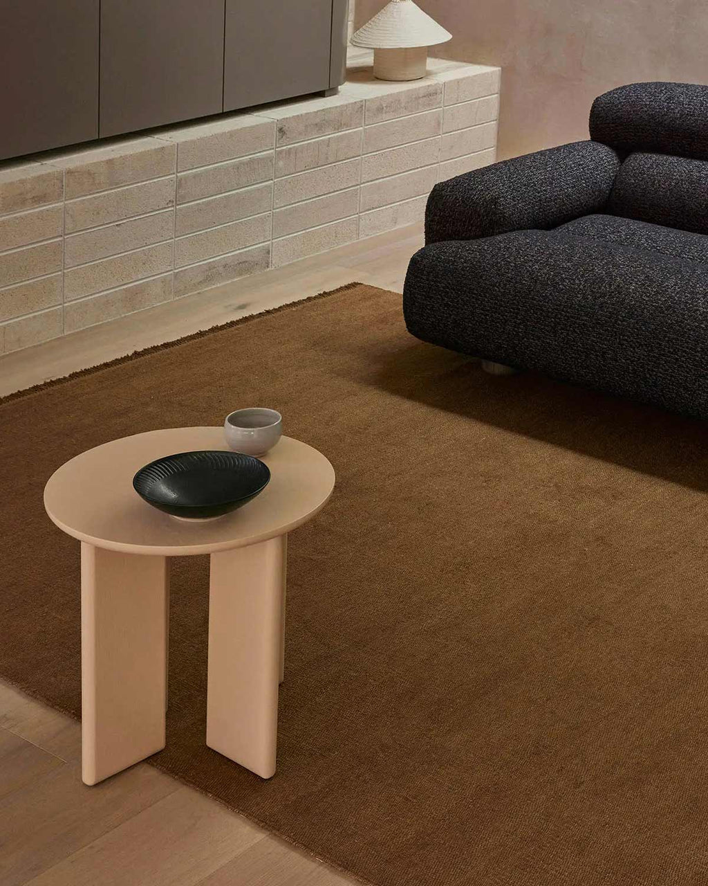 A sitting room with a modern designer coffee table and a warm mid-toned brown floor rug made with 100% linen. 