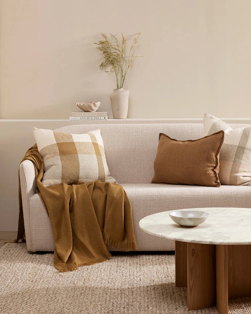 Tha Baya cumin-brown linen cushion with flanged edge, decorating a couch in a contemporary home