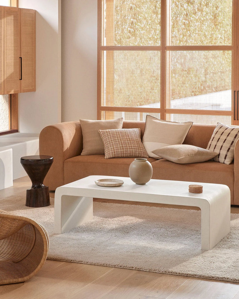 A stylish living room in warm beige and brown tones, featuring designer cushions by Weave Home nz