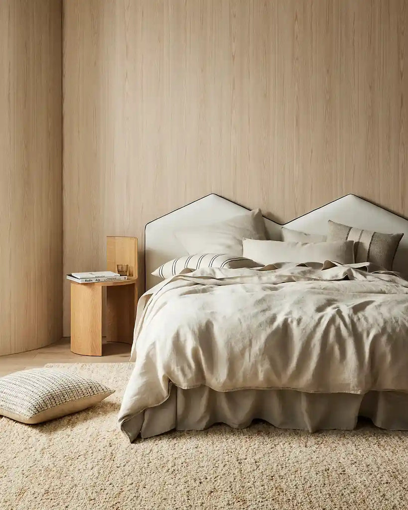 A bedroom setting featuring ravello linen in colour 'bone' and featuring the Vinnie striped cushion