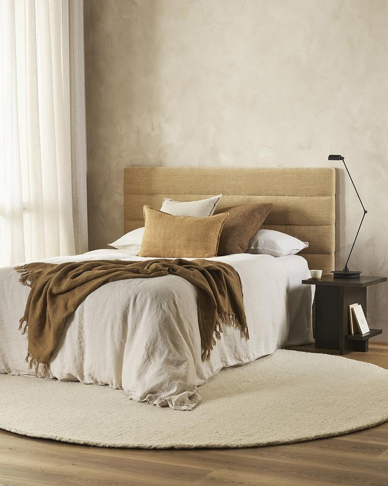 The round, Dorset, boucle weave wool and merino floor rug by Baya in a natural white seen In a stylish bedroom setting