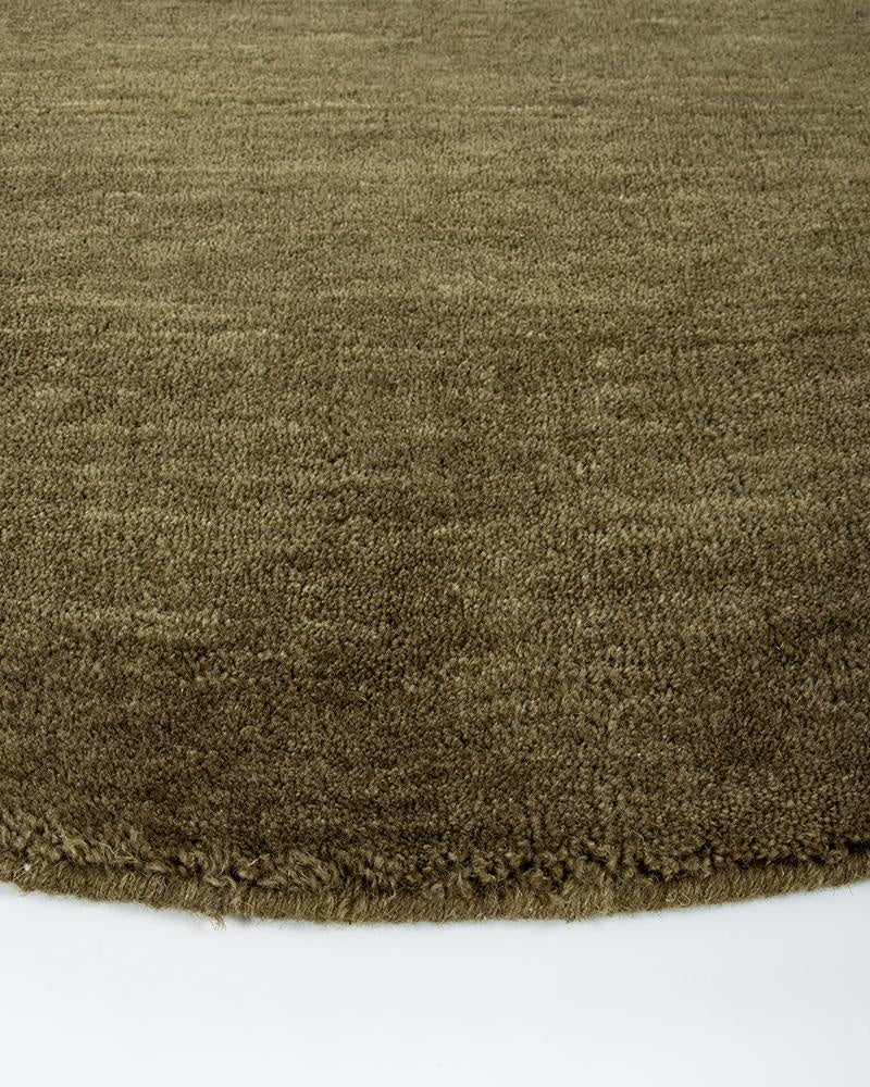 Perspective close up of a round rug showing the wool pile and green colour of the Sandringham Moss by Baya