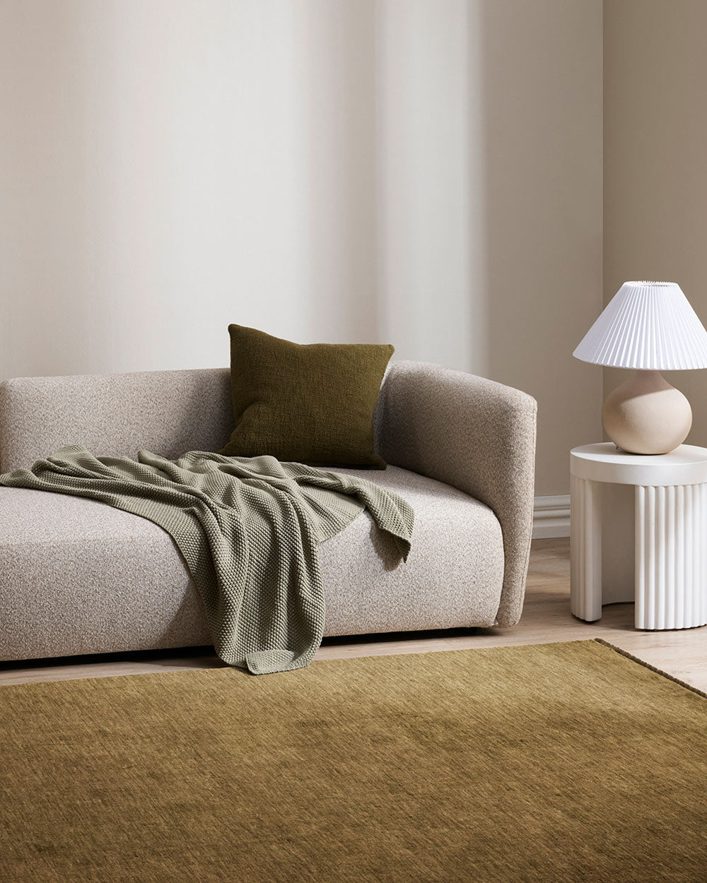 A minimalistic lounge with grey and green tones and a floor rug in 100% wool by Baya. 