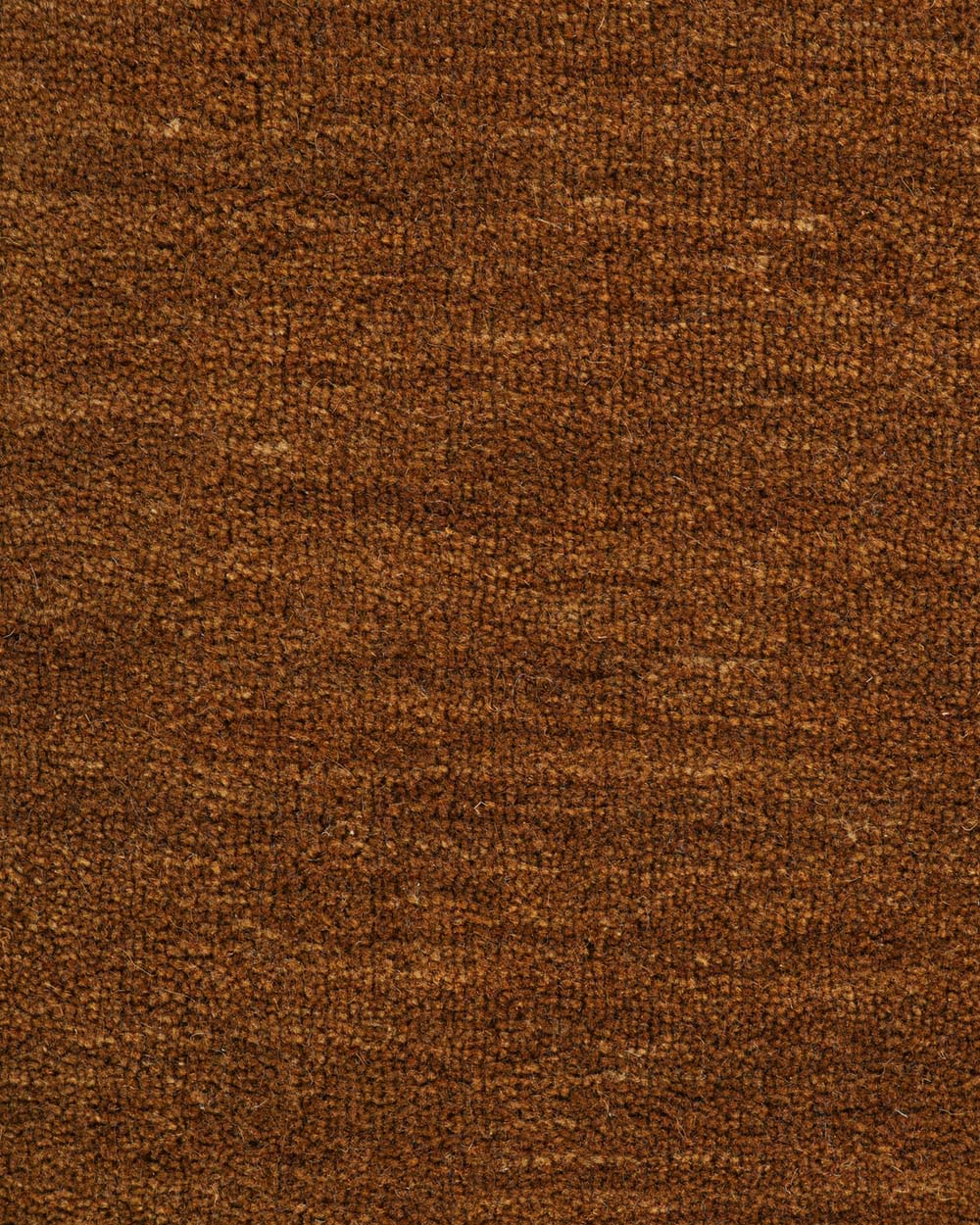 A close up image of the weave of a warm brown wool floor rug. 