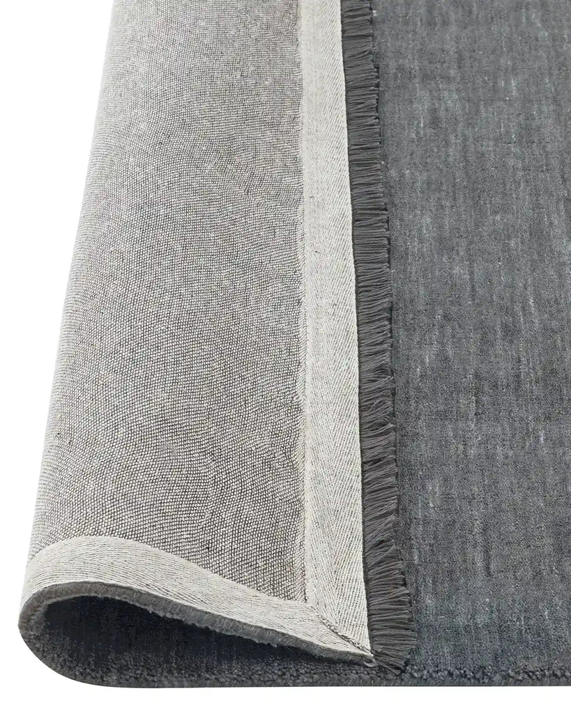 Grey Floor rug , the Silvio wool rug in colour 'fog' by Weave nz rolled to reveal underneath