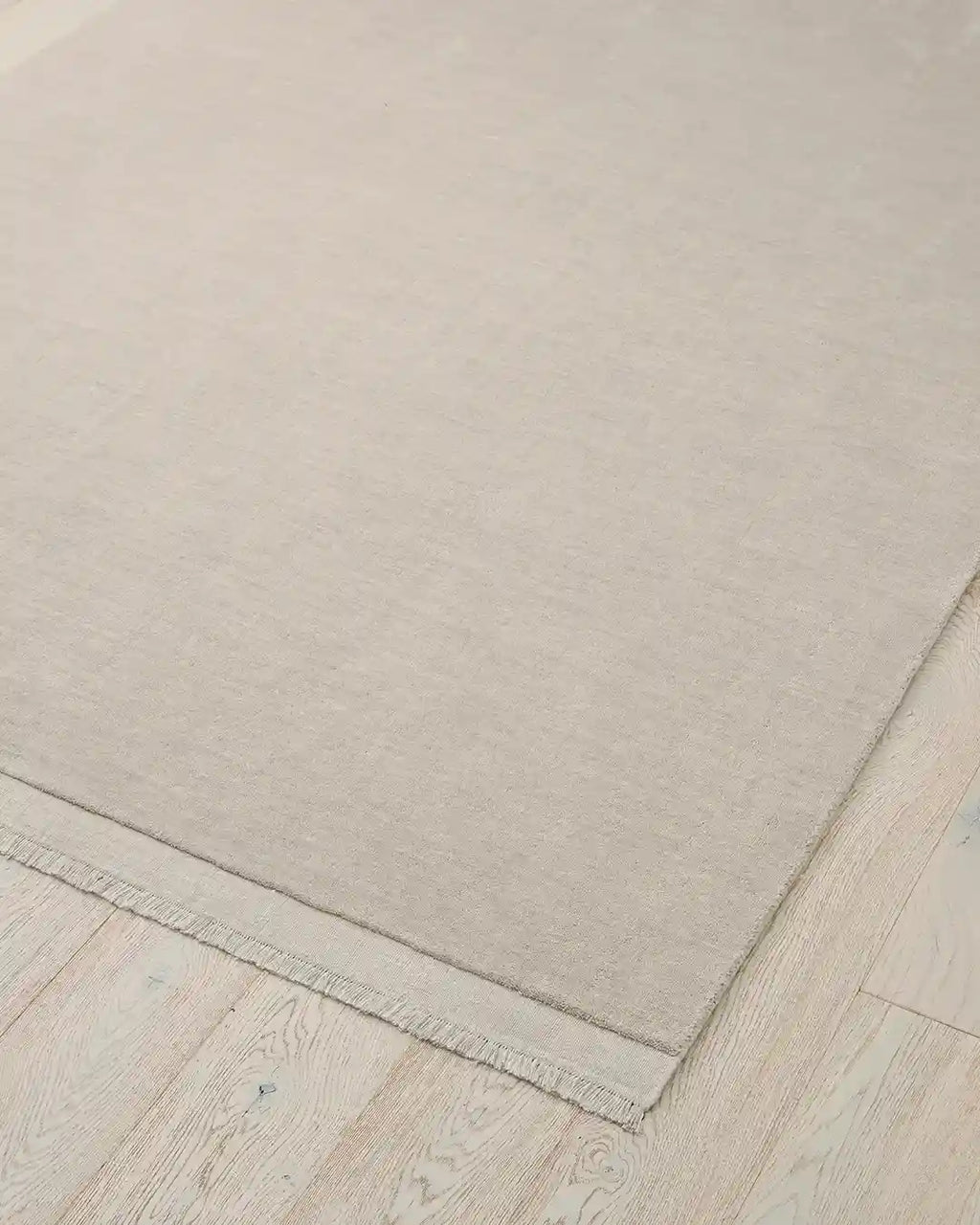 The Silvio wool floor rug in a neutral creamy ecru colour, seen from above