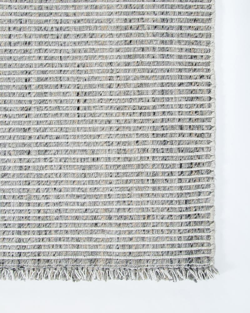 The Rhodes Slate Grey outdoor rug by Baya, seen from above, showing a white and grey textural weave and fringe detail