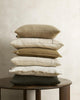 A beautiful stack of linen and cotton cushions in mostly cream, brown and white tones with green highlights