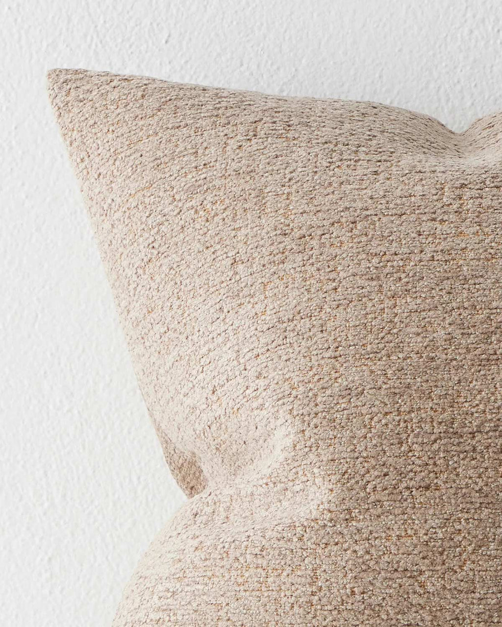 A corner view of a soft textural beige and brown cushion. 