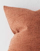 A close up image of a softly textured cushion in a vibrant rust orange tone. 