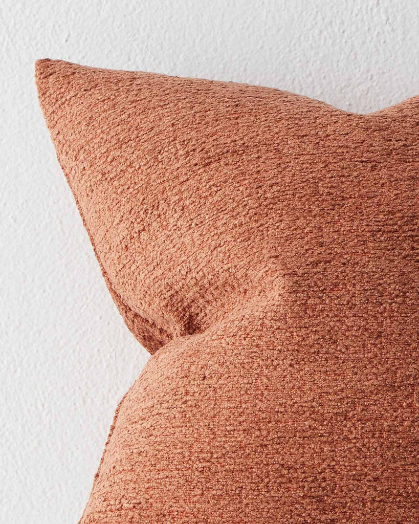 A close up image of a softly textured cushion in a vibrant rust orange tone. 