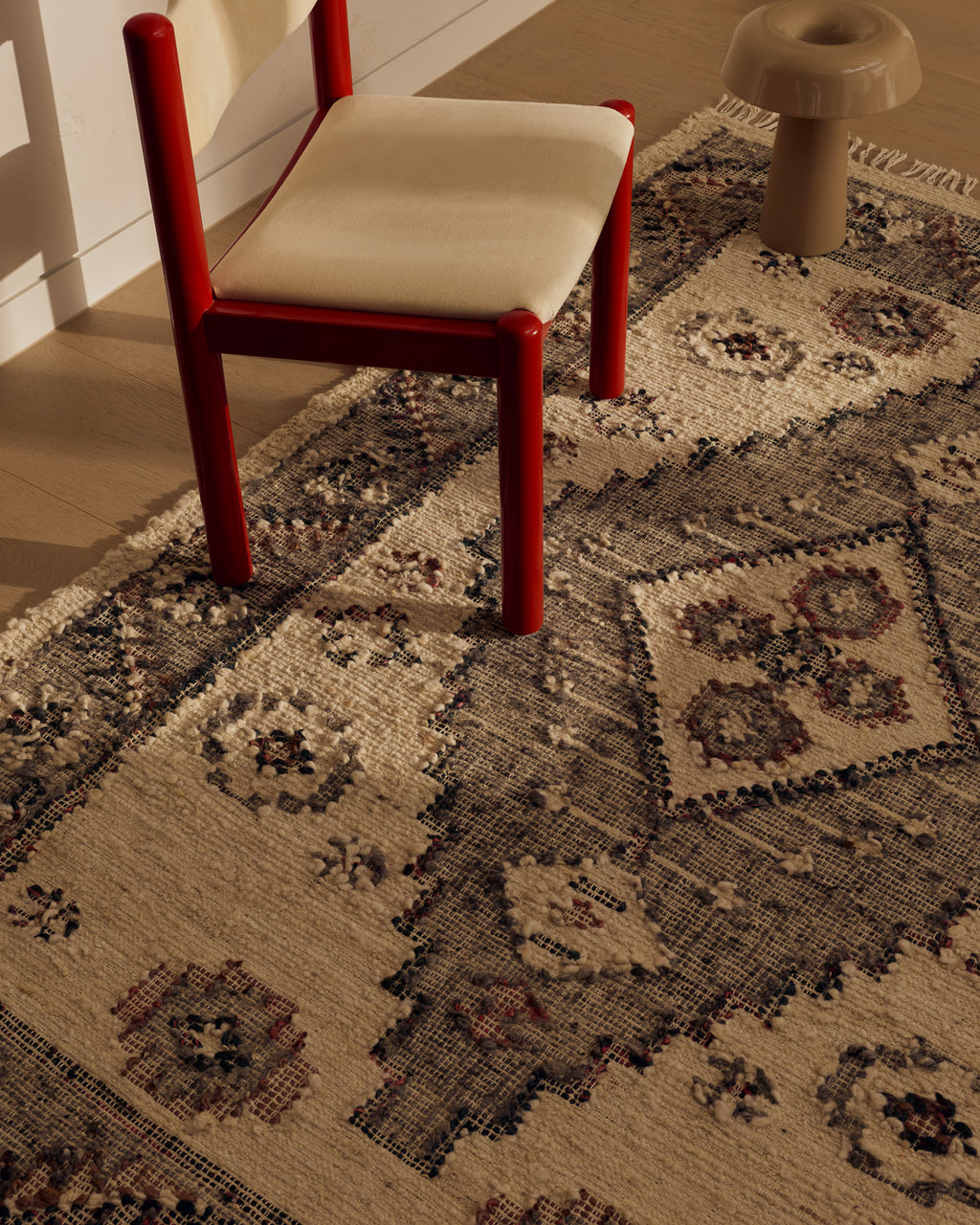 Close view of the Tribe Home Ellora wool and jute rug's diamond motif beside a red chair