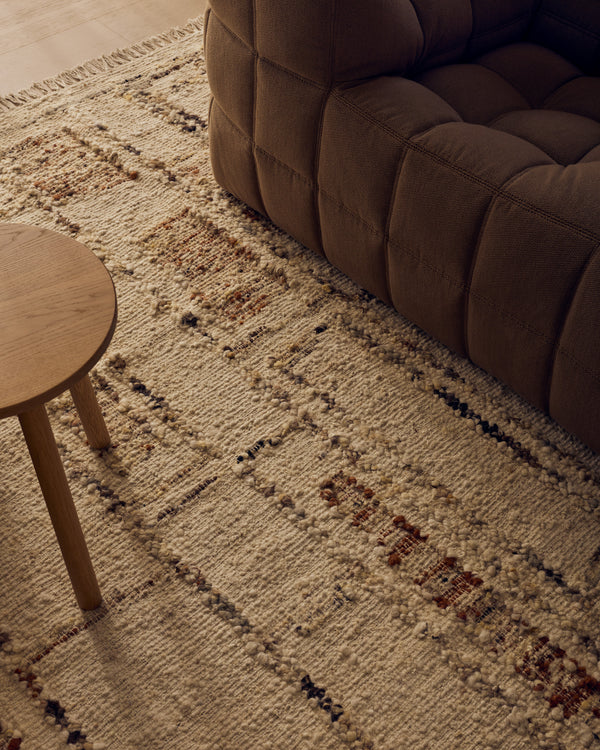Close view of the Tribe Home Rama wool and jute rug in Cinnamon beside a sofa and side table
