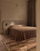 Tribe Home Rama wool and jute rug in Sienna beside a bed in a bedroom