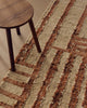 Close view of the Tribe Home Tulsi wool and jute rug in Paprika beside a timber stool