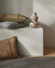 Decorative cushions and a vase on a white surface with a neutral background