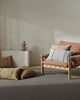 Sofa with cushions and a vase on a white pedestal in a minimalistic room.