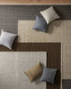 Patterned rug with various colored cushions on a wooden floor.
