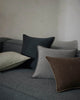 Grey sofa with various coloured designer cushions by Weave Home, against a neutral wall