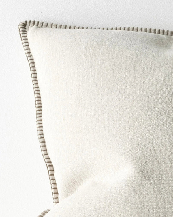 Close up of a Beige pillow with an elegant brown stitch detail on a white background