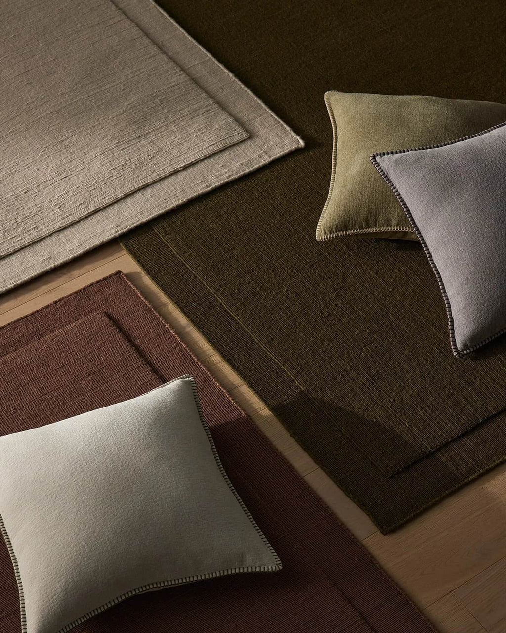 Three beautiful NZ wool rugs called 'Cassio' in beige, burgundy and chocolate brown with stylish cushions on top