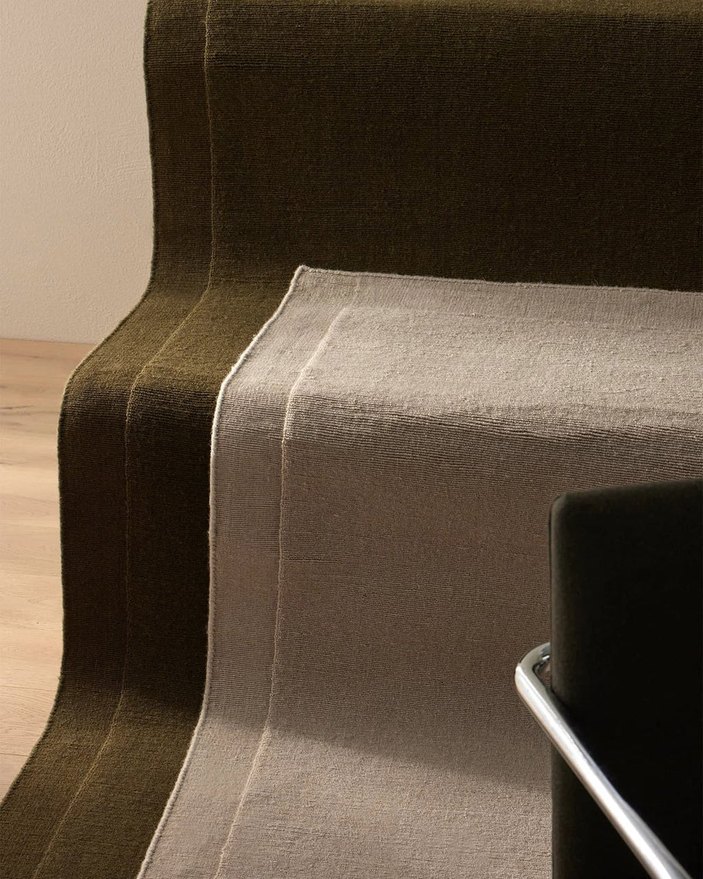 Two NZ wool rugs by Weave laid out on stairs with the corner of a chair