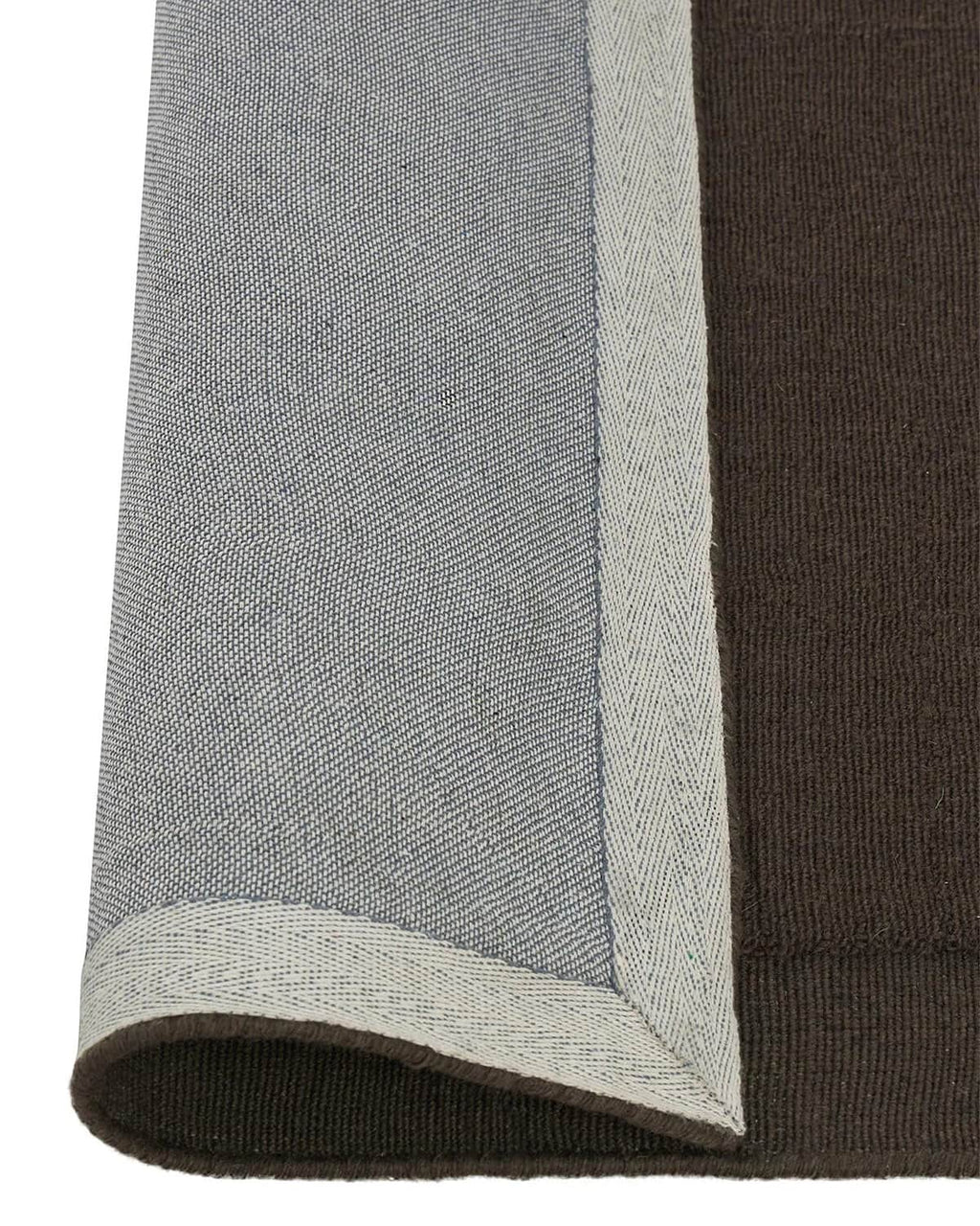 A Chocolate brown NZ wool floor rug with cut border, by Weave Home, with edge rolled to show underlay
