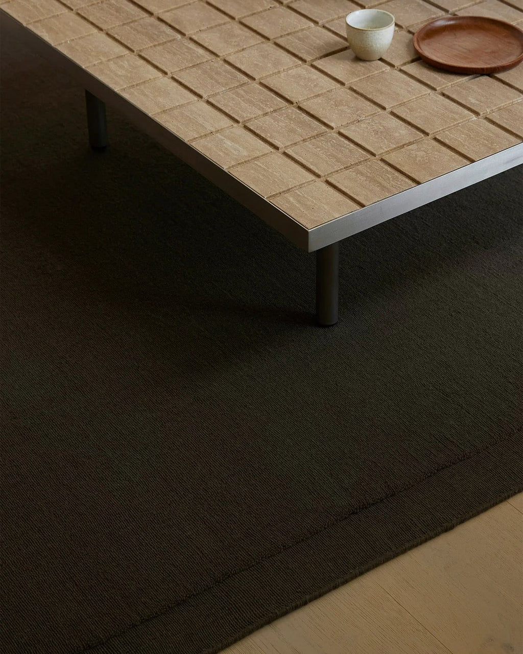 Chocolate brown 'Cassio' wool rug by Weave Home, seen under a wooden table