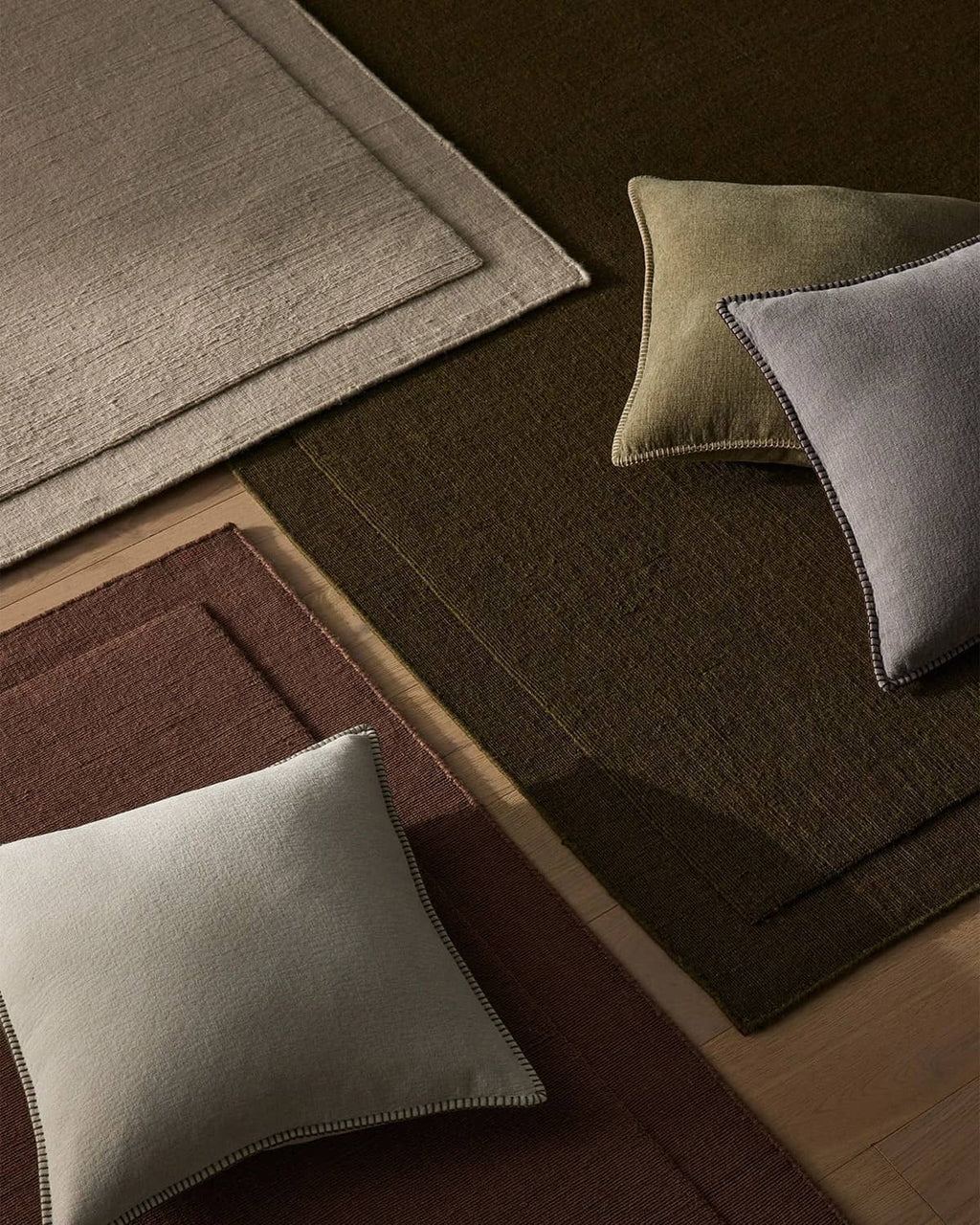 NZ wool rugs in chocolate brown, burgundy and beige with a scatter of designer cushions