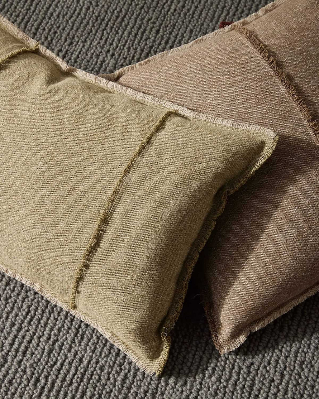 Close-up of textured grey floor rug with two cushions. 