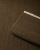 Close-up of a brown-green 100% wool textural floor rug with a sample laid atop it. 