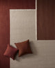 Beige rug with two brown cushions on a brown floor.