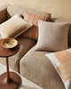 A selection of plain and patterned cushions in earthy brown tones on a modern couch, by Weave Home