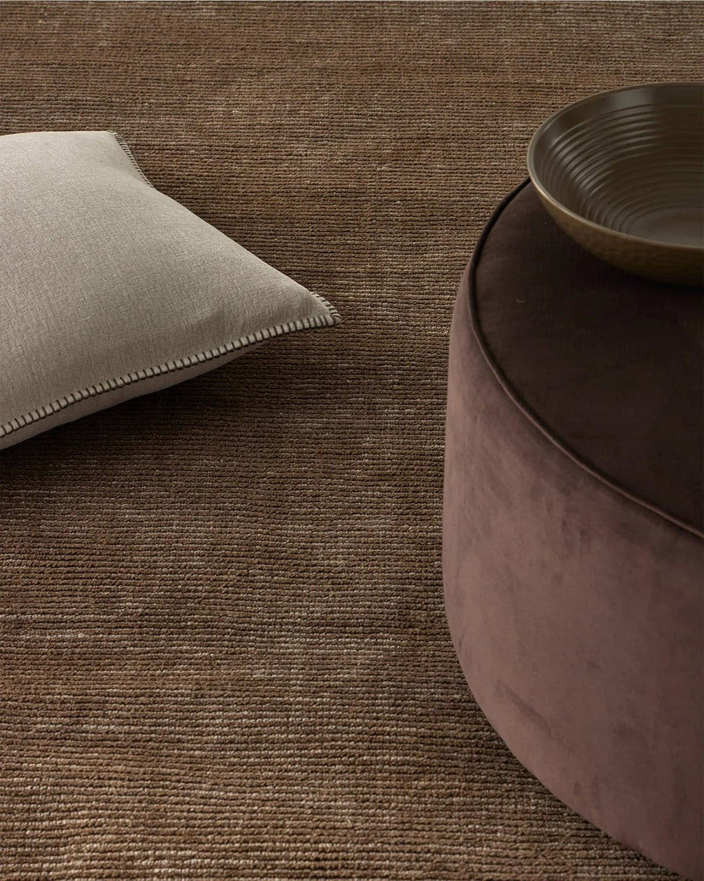 Weave Home Textured brown rug with a cushion and ottoman