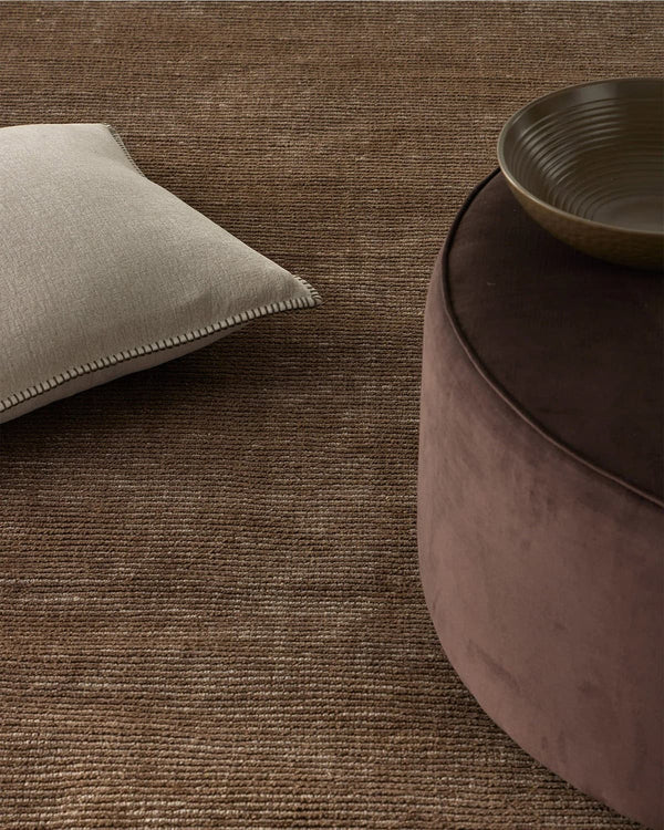 Weave Home Textured brown rug with a cushion and ottoman