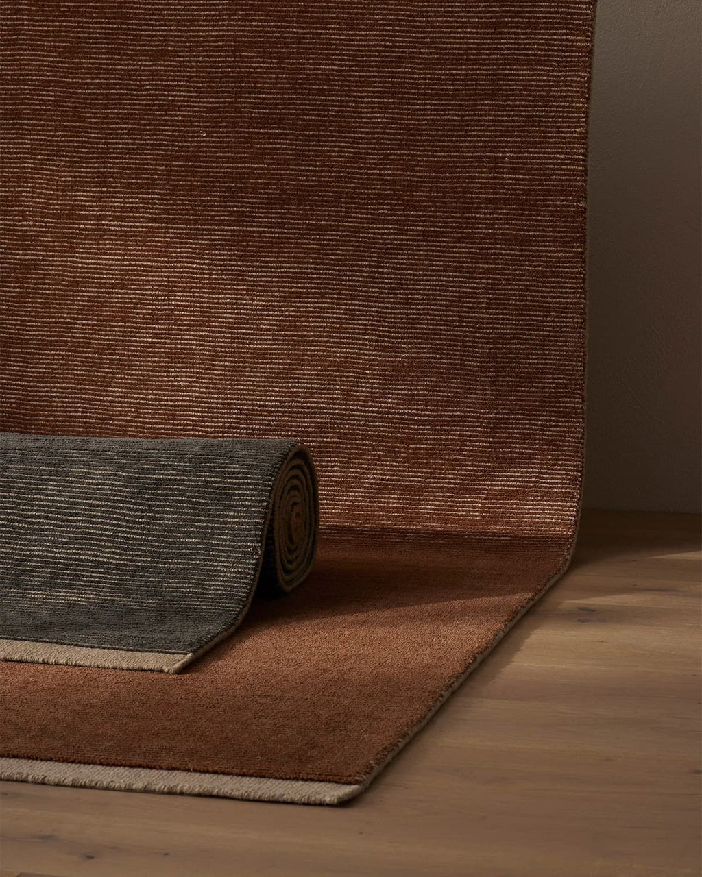 Weave Home NZ wool amber textured rug partially unrolled on a wooden floor with a brown rug