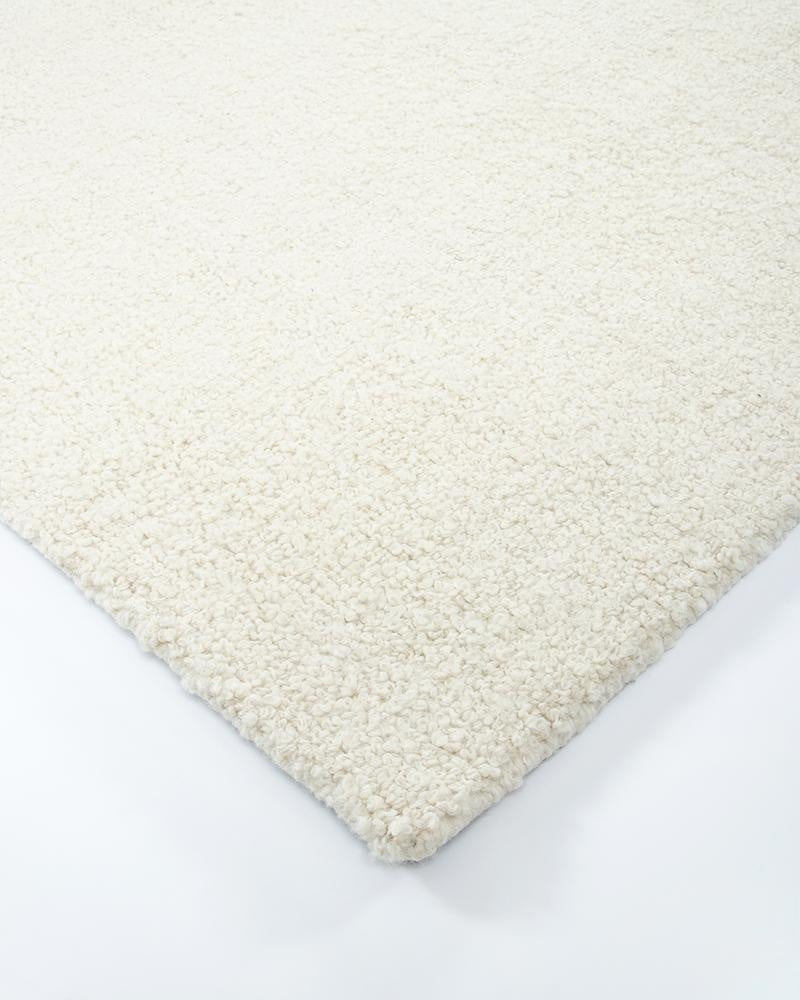 Corner close up of a light creamy-white wool floor rug with a boucle style weave - the Dorset natural White by Baya.