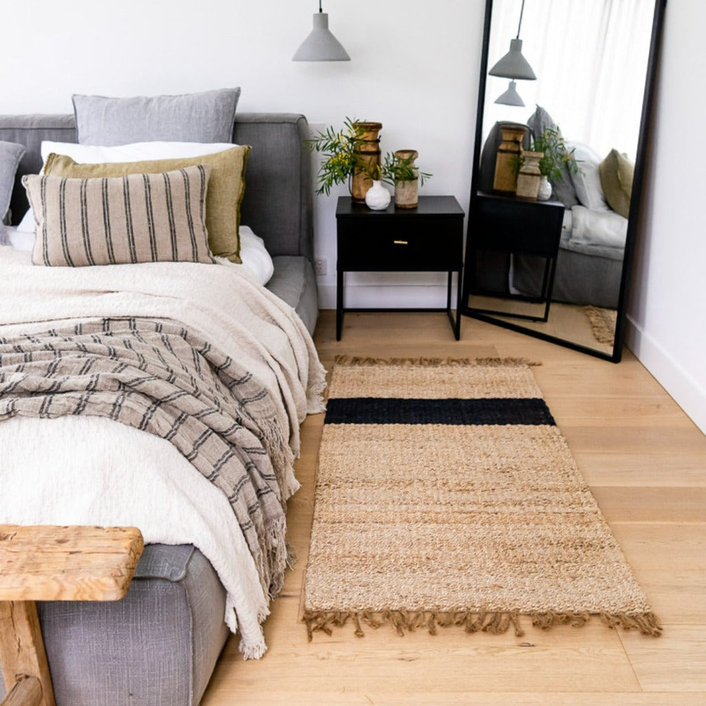 A modern bohemian style bedroom with a jute mat by the bed. 