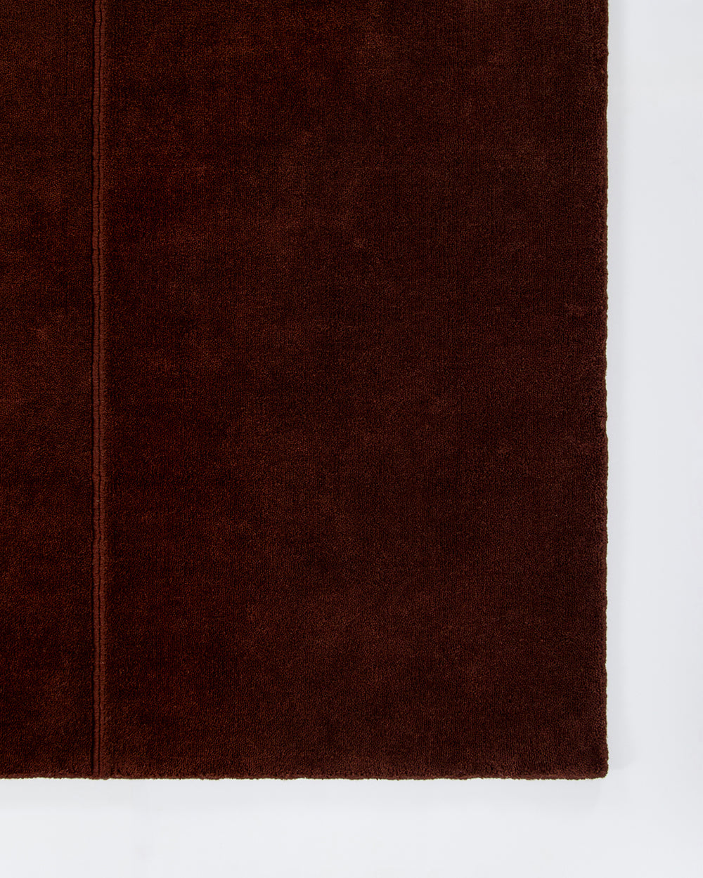 Baya Bastion NZ wool floor rug in Claret, close view of a corner showing the pile and a fine lengthwise line.