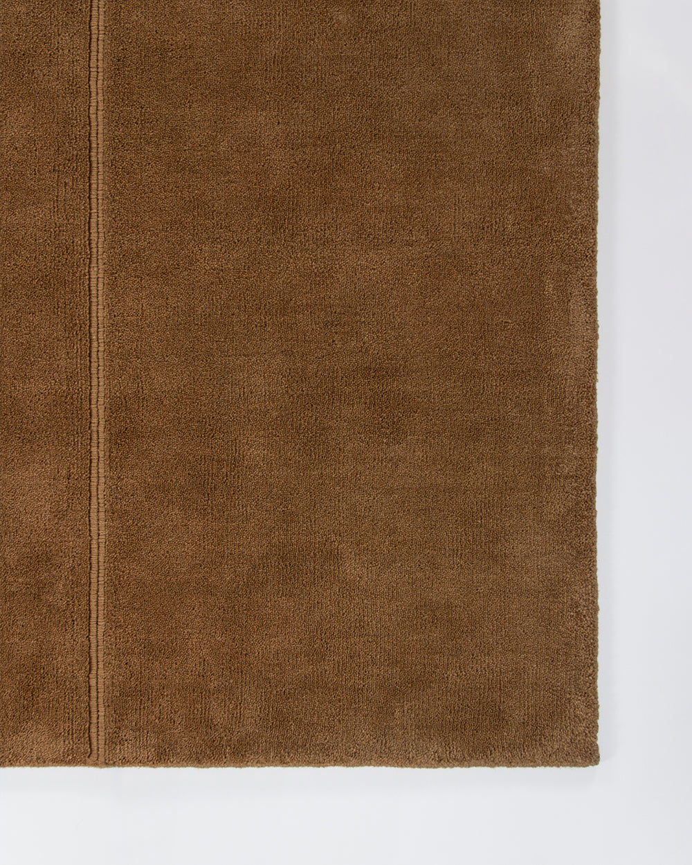 Baya Bastion NZ wool floor rug in Hazelnut, close view of a corner showing the pile and a fine lengthwise line.