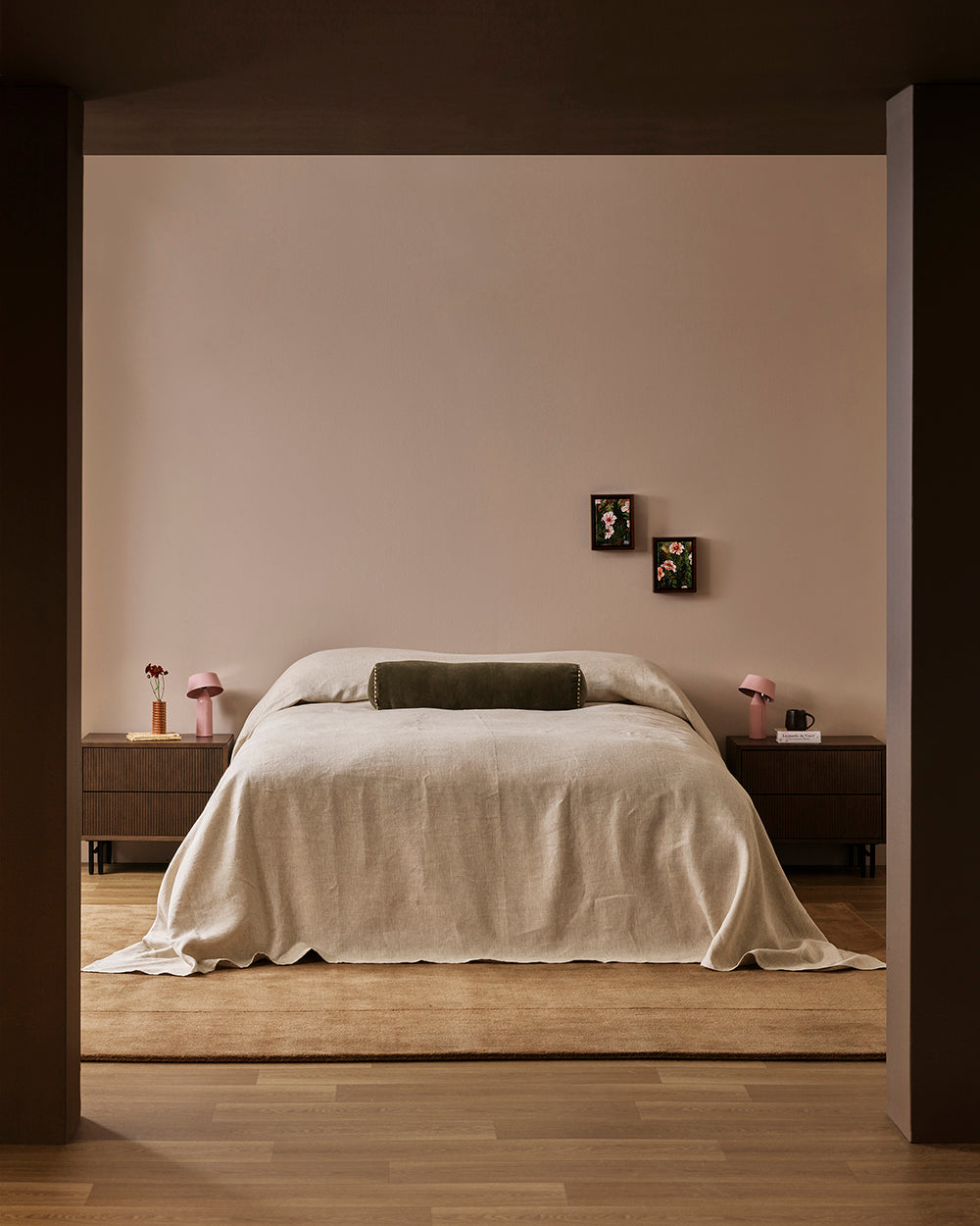 Baya Bastion NZ wool floor rug in Hazelnut, styled under a bed with a linen throw, seen through a doorway in a bedroom.