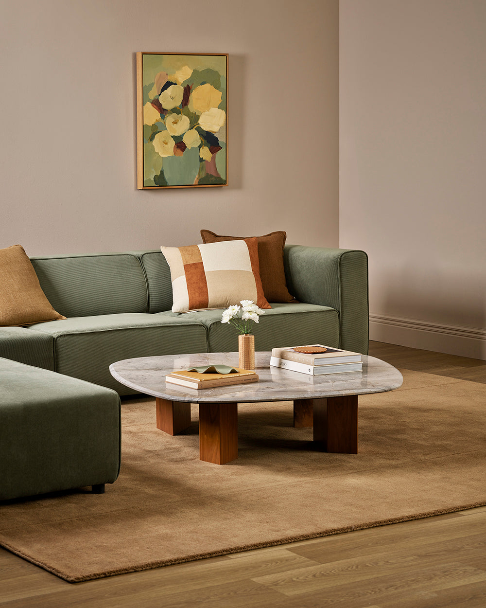 Baya Bastion NZ wool floor rug in Hazelnut, styled under a marble coffee table in a living room with a sage green sofa.