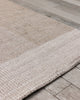Baya Bedrock Indoor and Outdoor Floor Rug in Sand, close angled view on timber flooring showing the pale sand field meeting the lighter oatmeal striped border and edge binding.