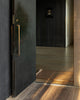 Baya Carla NZ wool floor mat in Cocoa, styled at a dark entranceway beside an open door.