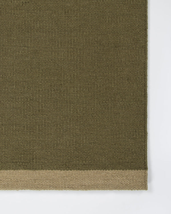 Baya Carla NZ wool floor mat in Military, close view of the woven texture and the pale sand end band.